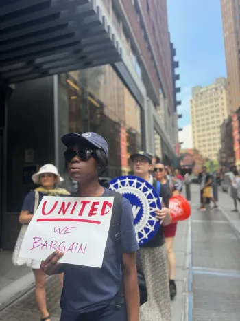 ALAA member on strike holding sign that says "United We Bargain"